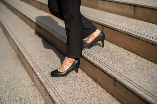 Cropped photo of businesswoman walking up stairs out side, wearing high heels. High quality photo