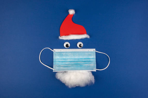 istock handmade santa clause with moth protection, face mask, red cap and beard, as a symbol for impact in covid virus in Christmas season 1286987827