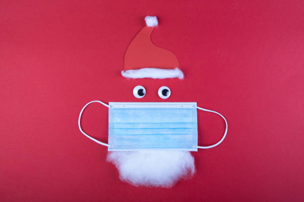 istock handmade santa clause with moth protection, face mask, red cap and beard, as a symbol for impact in covid virus in Christmas season 1286987932