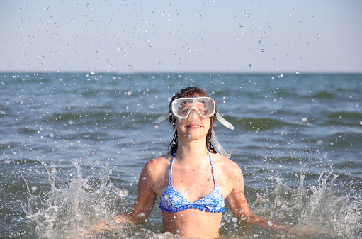 young girls have a lot of fun with diving mask plays by splashing sea water in the air in summer