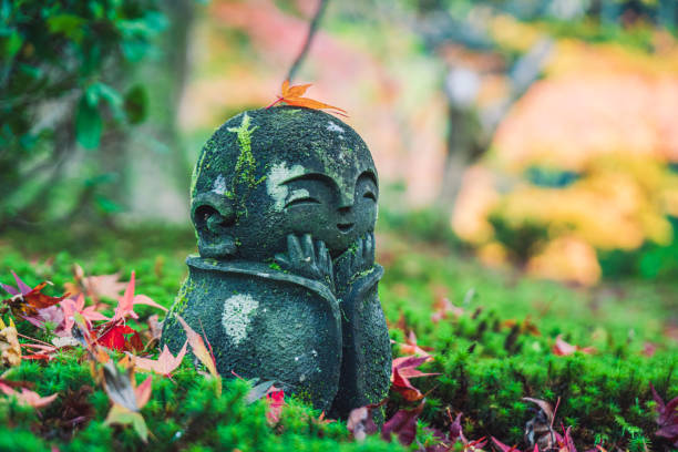 istock Small jizo buddhist statues in the moss with fallen red maple leaves surrounding. 1286990756