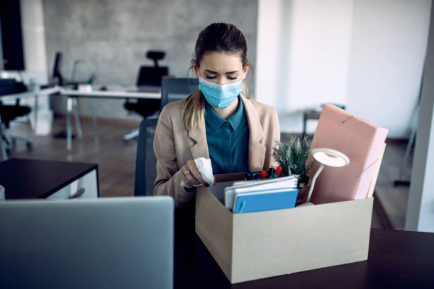 istock Sad businesswoman packing her belongings while getting fired from work due to COVID-19 pandemic. 1286990807