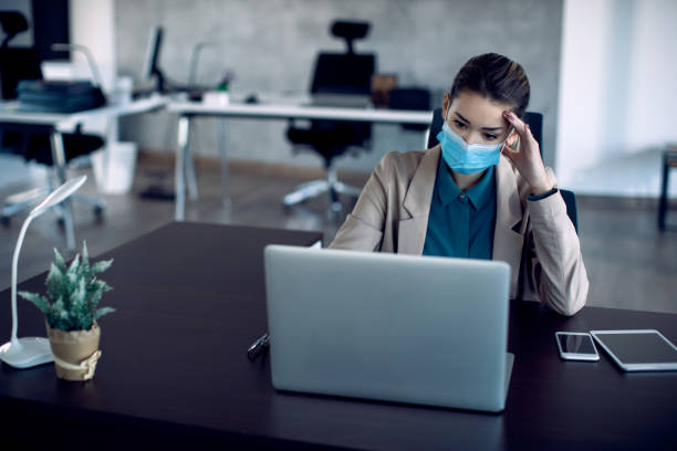 istock Distraught businesswoman with face mask reading problematic e-mail on laptop in the office. 1286992690