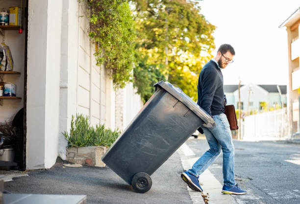 Hauling garbage Man pulling a wheeled dumpster out of his garage while going to work workplace absence stock pictures, royalty-free photos & images