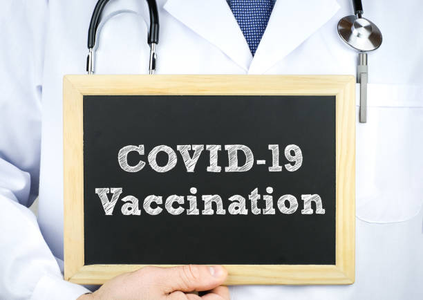 istock COVID-19 Vaccination - Doctor holding chalkboard message 1286997720