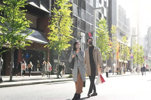 Asian mid-adult couple shopping and dating on street of Ginza, famous shopping area in Tokyo, Japan