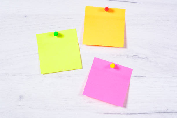Three colored paper notes with pins on a white wood background