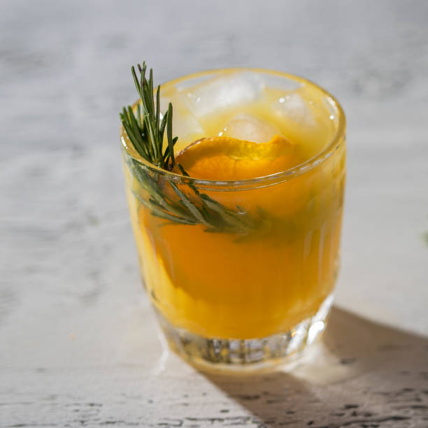 istock Refreshment drink with orange  and rosemary herb on white concrete background. Summertime beverage for hot days. 1287004705
