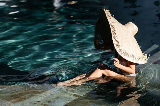 istock Woman in big straw hat relaxing at pool. 1287004857