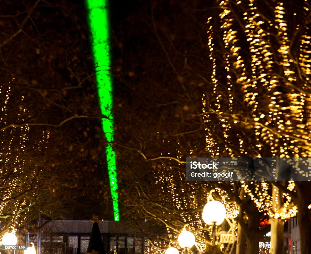 Laser beam over 1.5 km through the city center, sign of optimism in Corona Lockdown. With winterly decorated trees at the edge of the pedestrian zone Light Painting Stock Photo