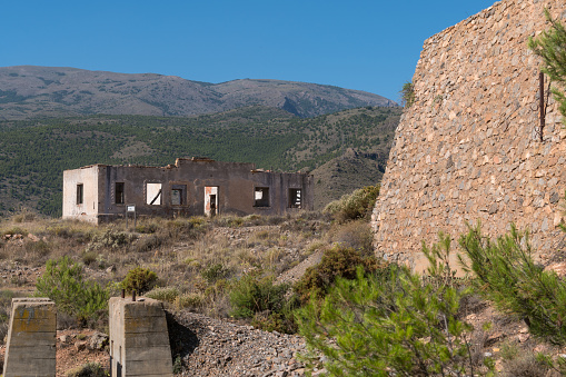 Old and abandoned buildings in a mining complex, the buildings are built in bricks, there is a stone wall, it is a mountainous area and the sky is clear