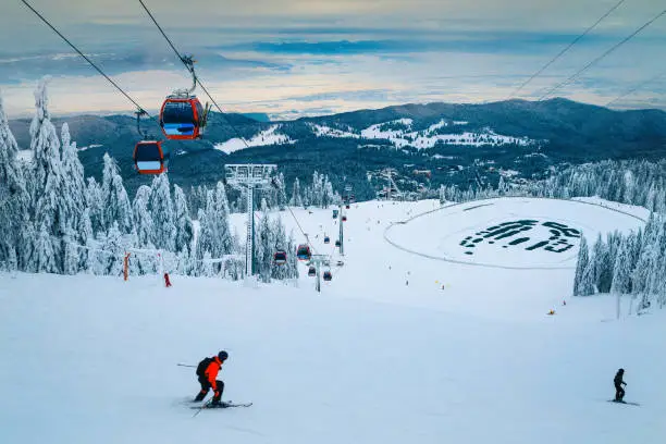 Photo of Ski slopes with active skiers and snow covered trees, Romania