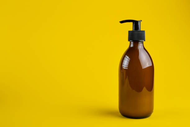 istock Cosmetics containers mockup. Glass cosmetic container with dispenser on a yellow background. Beauty products for body care. 1287008416