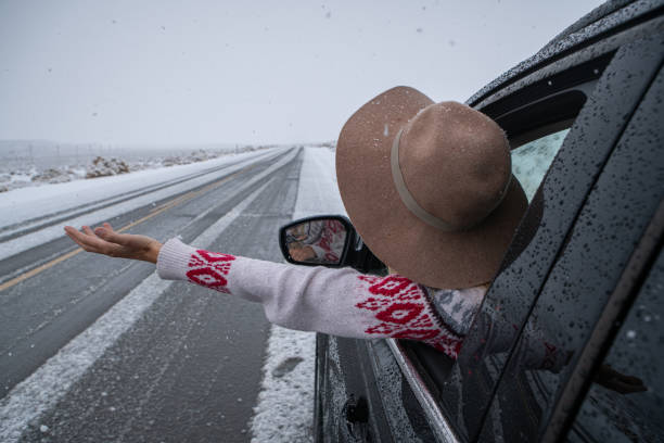 istock Woman inside car pulls out hand to touch snow 1287013018