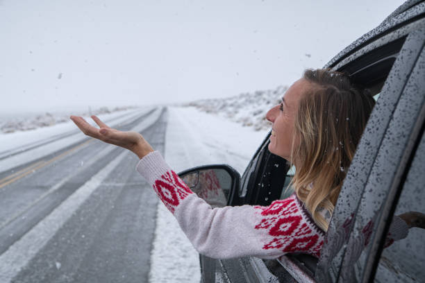 istock Woman inside car pulls out hand to touch snow 1287013044
