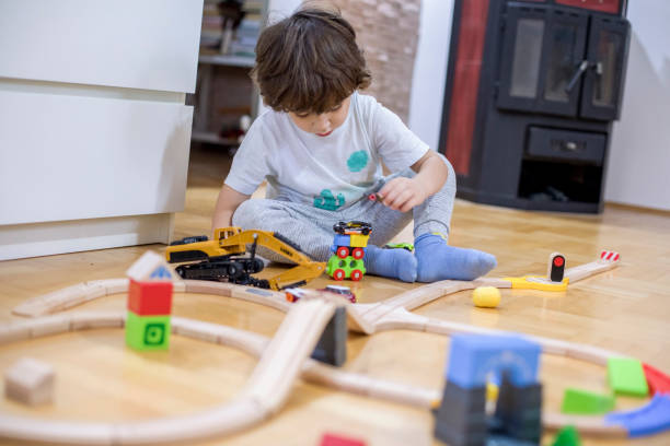 istock Beautiful little boy playing with a railroad train toy. 1287016493