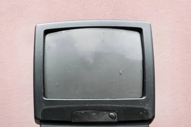 old broken tv in plastic frame with empty screen aged wall background front view