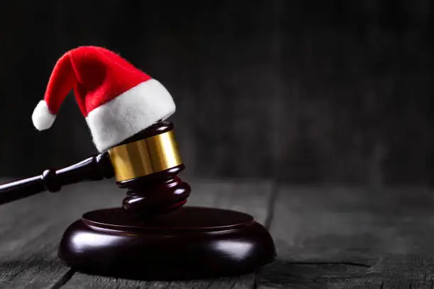 Photo of Santa Claus hat on Judge Gavel on wooden rustic background