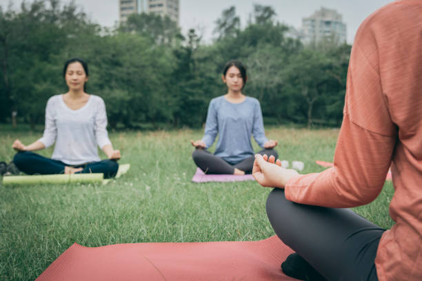 istock chinese young women practicing yoga at public park 1287017641