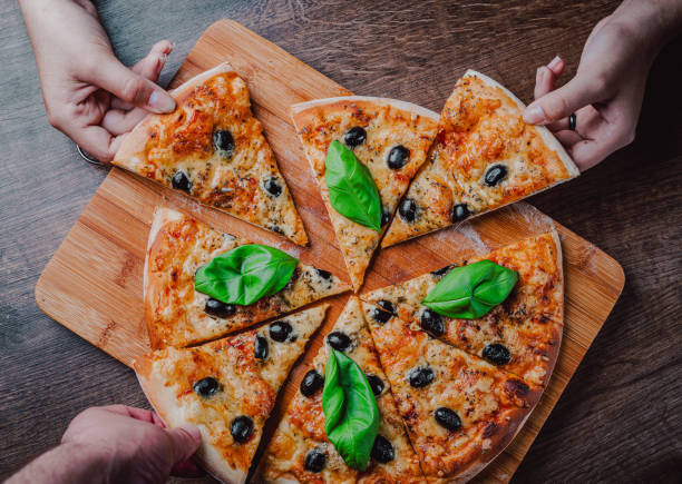 istock hands take a slice of Pizza with Mozzarella cheese, Tomatoes, pepper, olive, Spices and Fresh Basil. Italian pizza. Pizza Margherita or Margarita on wooden table background 1287019143