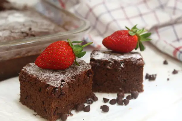 Chocolate brownies with chocochips springkle and white icing sugar topped with fresh strawberry