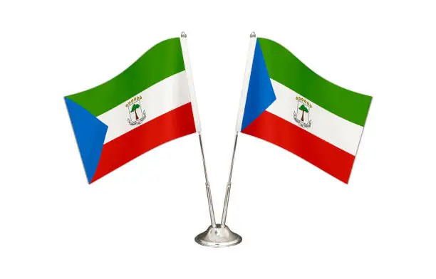 Equatorial Guinea table flag isolated on white ground. Two flag poles with flags and Equatorial Guinea flag on the table.