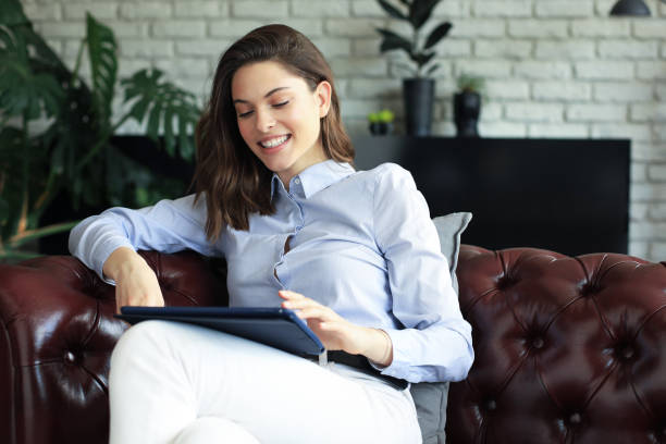 istock Young smiling woman with tablet pc on the sofa. 1287025599