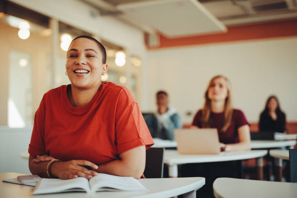 Smiling female student sitting in university classroom Female student sitting in university classroom and smiling. Woman paying attention in the class. adult student stock pictures, royalty-free photos & images