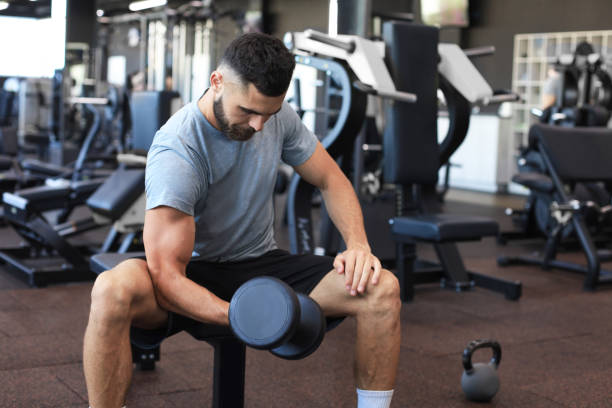 istock Fit and muscular man doing biceps workouts with dumbbells in gym, copy space. 1287027048