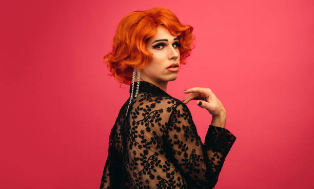Drag queen with stunning look Man dressed as woman looking over his shoulder. Glamarous drag queen against red background. gender fluid photos stock pictures, royalty-free photos & images