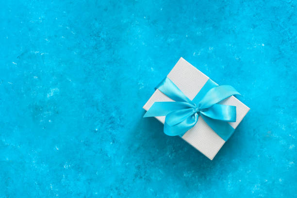 istock Gift box with blue ribbon on a blue grunge background. Top view, flat lay. 1287028189