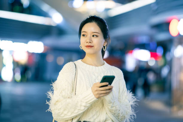istock Young woman using mobile phone at city night 1287028303