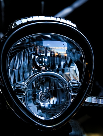 Chrome headlight on a classic motor cycle with white glass. Close up.