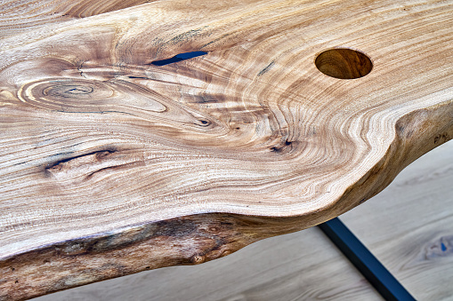 Live edge elm gaming desk countertop with metal base in a modern home office. Details close-up
