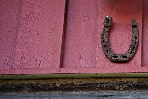 istock Old rusted horse shoe on a red barn wall for good luck. 1287031364