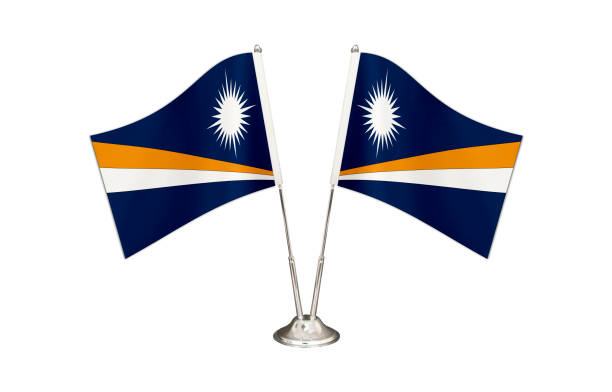 istock Marshall İslands table flag isolated on white ground. Two flag poles with flags and Marshall İslands flag on the table. 1287031869