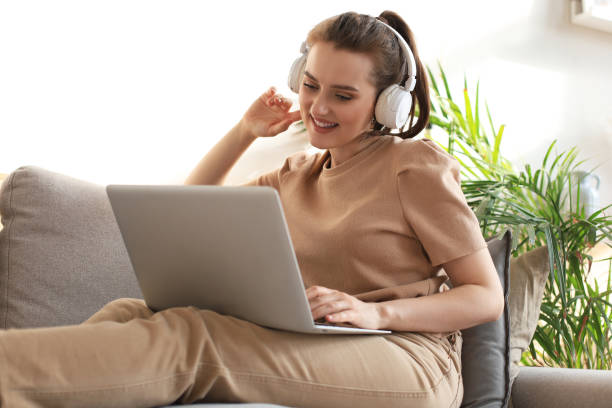 Smiling young woman with headphones and laptop on the sofa. Smiling young woman with headphones and laptop on the sofa 30132 stock pictures, royalty-free photos & images