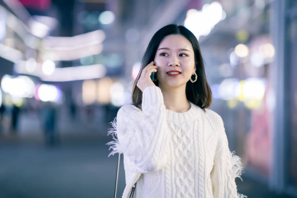 istock Young woman talking with friend using phone on the streets 1287034073