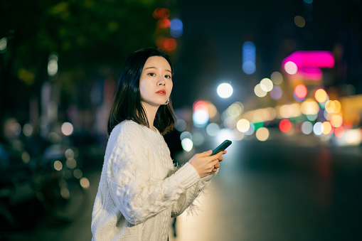 Young Asian female tourist using smart phone hailing a taxi