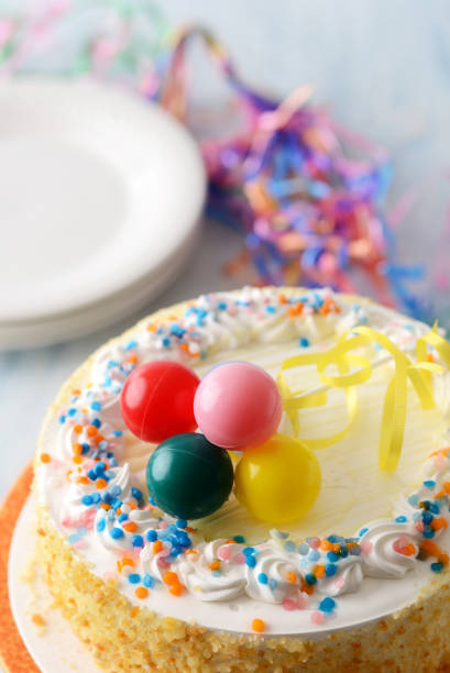 closeup of vanilla birthday cake with plastic colorful balloons on top