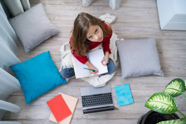 istock Cute girl on the floor writing in notebook 1287040365