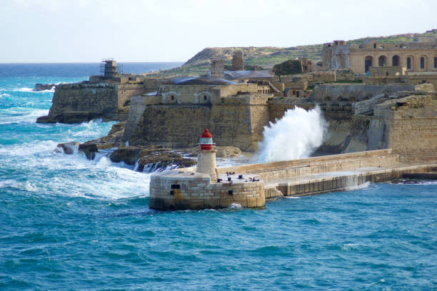 vista desde fort st elmo hasta el ricasoli grand harbour east breakwater y el faro rojo durante fuertes olas - st elmo fotografías e imágenes de stock