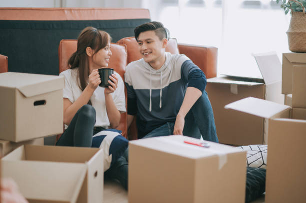 asia chinese couple sitting on floor resting after opening carton cardboard boxes in living room moving house asia chinese couple sitting on floor resting after opening carton cardboard boxes in living room moving house tenant stock pictures, royalty-free photos & images