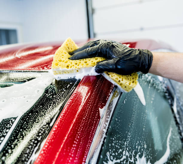 istock Worker washing red car with sponge on a car wash 1287044433