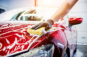 Worker washing red car with sponge on a car wash