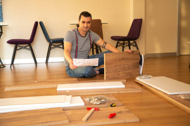 istock Man surrounded by unassembled furniture 1287045876