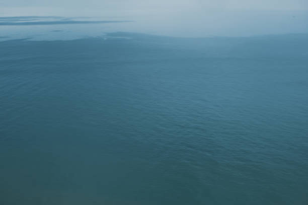 Blue skies with rolling rainclouds over a flat and calm sea