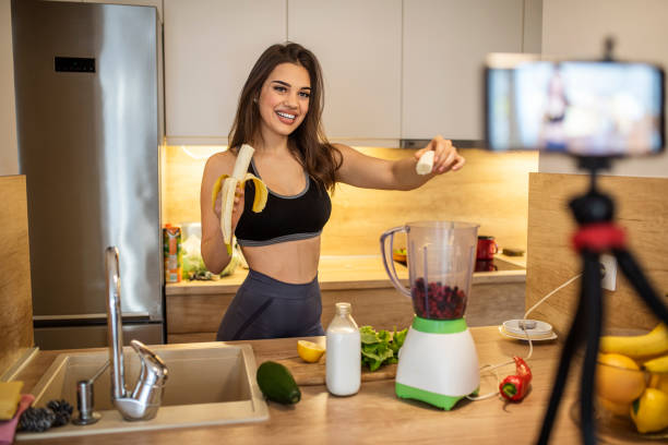 istock Young woman in kitchen recording video on camera. 1287047713