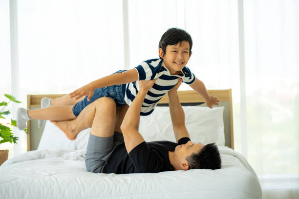 istock Asian father work from home caring boy son on bed at home 1287049203