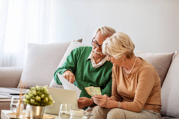 istock Senior couple counting bills at home. 1287052384